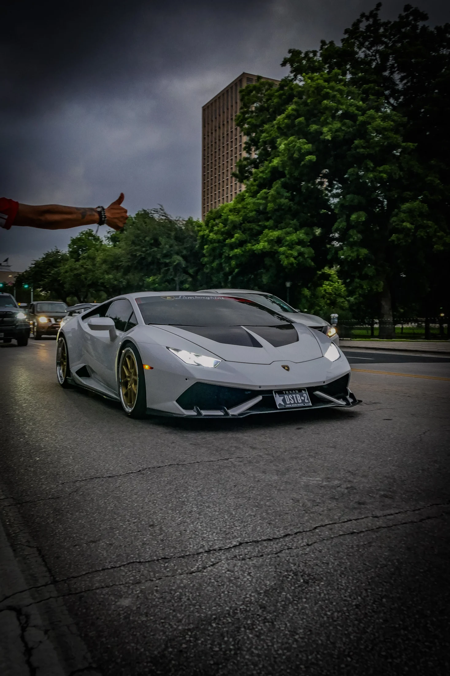 Gray Lamborghini on a city street beneath storm clouds